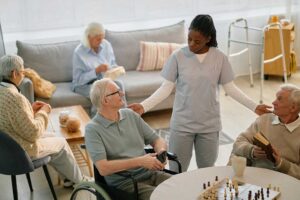 A caregiver helping an elderly resident walk down a sunlit hallway with handrails and cheerful decor.