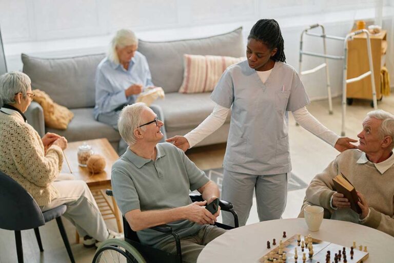 A caregiver helping an elderly resident walk down a sunlit hallway with handrails and cheerful decor.